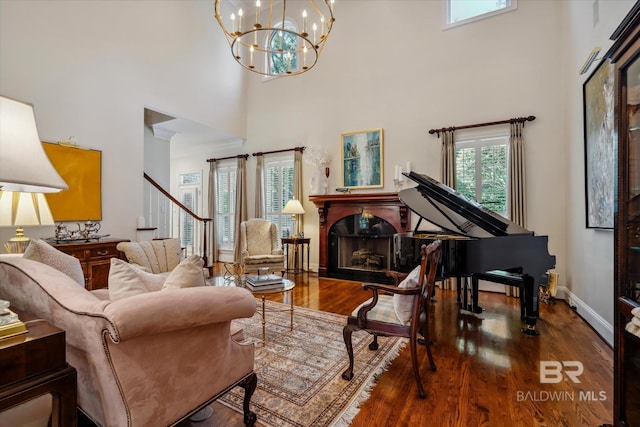 living area with a notable chandelier, a towering ceiling, a fireplace, and wood-type flooring