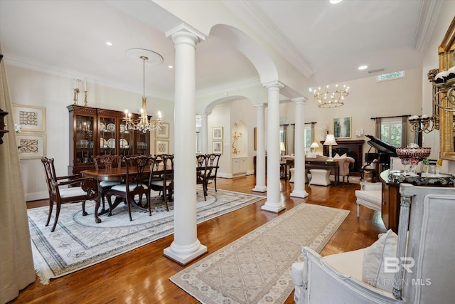 dining space featuring decorative columns, crown molding, an inviting chandelier, and dark hardwood / wood-style flooring