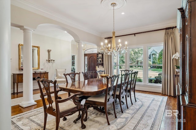 dining area featuring a notable chandelier, hardwood / wood-style flooring, ornamental molding, and decorative columns