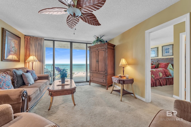 24522 Perdido Beach Blvd Unit 5617, Orange Beach, AL 36561 - living room featuring light carpet, a water view, ceiling fan, a wall of windows, and a textured ceiling