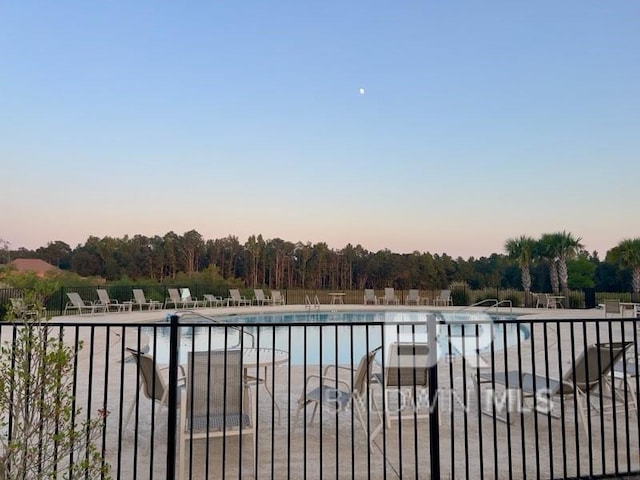 pool at dusk featuring a patio area