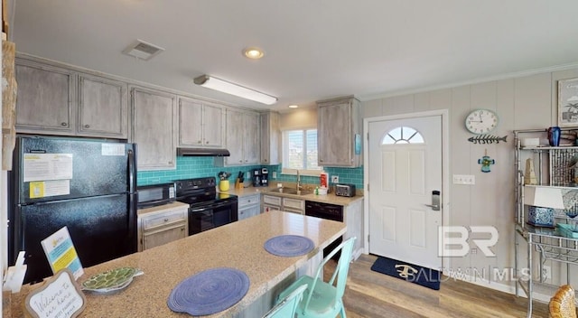 kitchen with tasteful backsplash, black appliances, sink, crown molding, and light hardwood / wood-style flooring