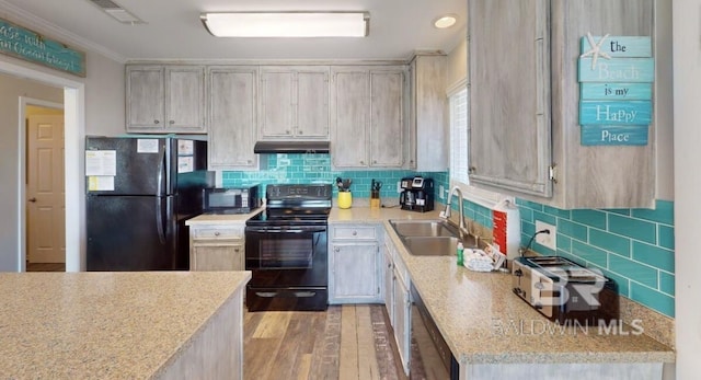 kitchen with black appliances, sink, backsplash, light wood-type flooring, and light stone counters