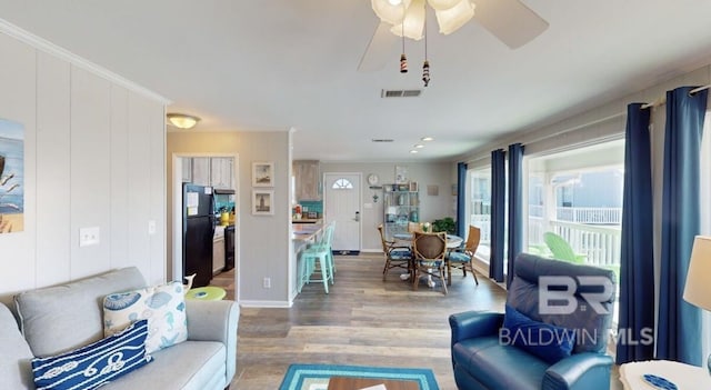 living room featuring ceiling fan, crown molding, and wood-type flooring