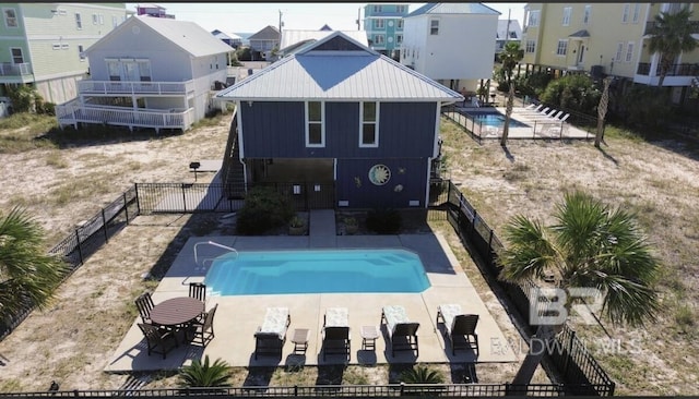rear view of property featuring a fenced in pool and a patio