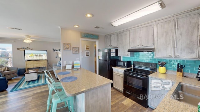 kitchen featuring black appliances, sink, backsplash, ceiling fan, and light hardwood / wood-style flooring