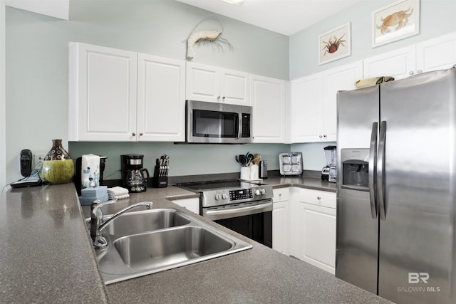 kitchen featuring appliances with stainless steel finishes, dark countertops, white cabinets, and a sink