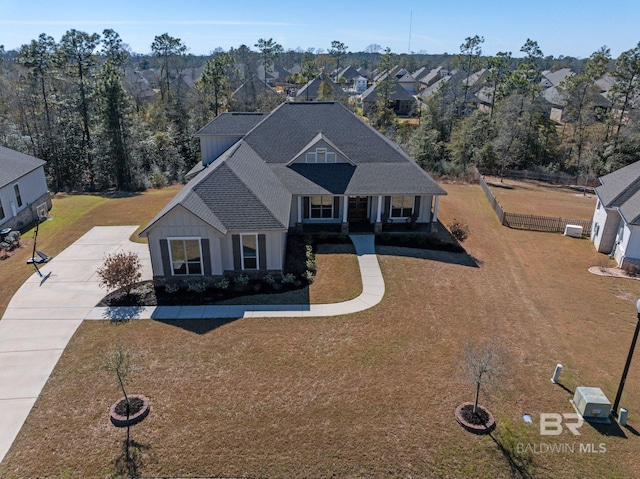 view of front of property with concrete driveway, a front lawn, roof with shingles, and fence