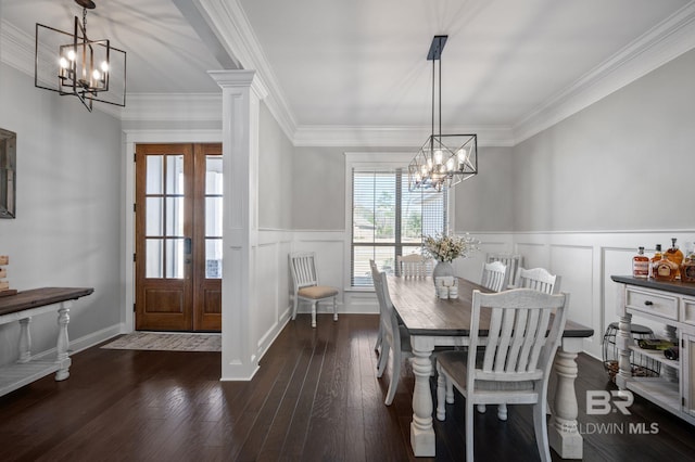 dining room featuring wainscoting, wood-type flooring, crown molding, a chandelier, and a decorative wall