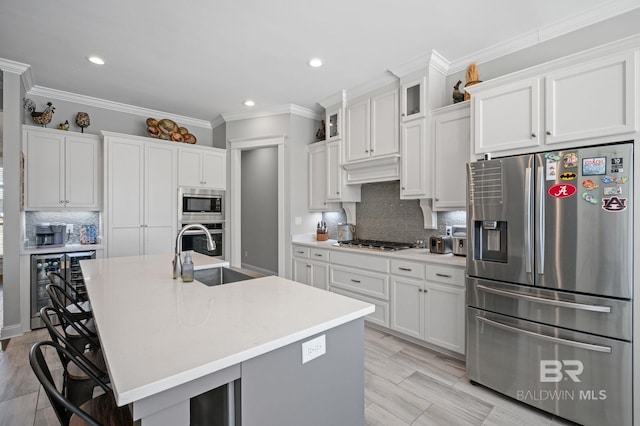 kitchen with wine cooler, appliances with stainless steel finishes, white cabinets, and a sink