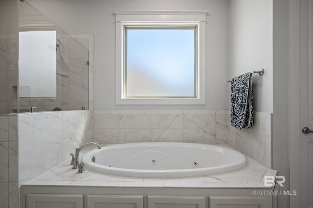 full bathroom with tiled shower and a jetted tub