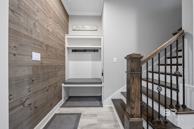 mudroom featuring wood walls, baseboards, and ornamental molding