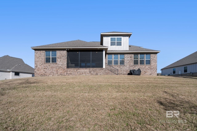 rear view of house with brick siding, a lawn, board and batten siding, and a sunroom