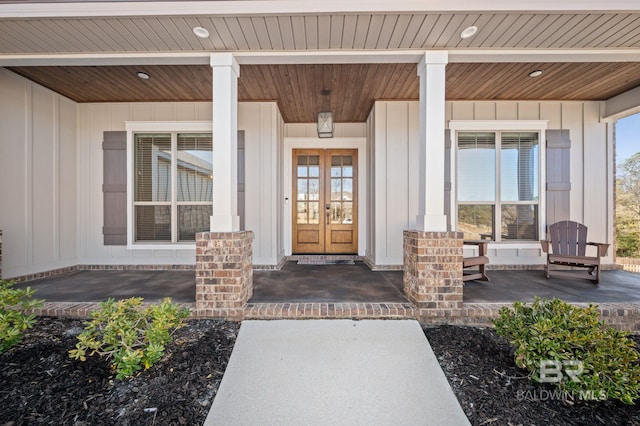 view of exterior entry with a porch, board and batten siding, and french doors