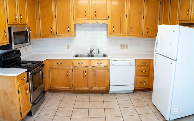 kitchen with tasteful backsplash, light countertops, appliances with stainless steel finishes, brown cabinetry, and a sink