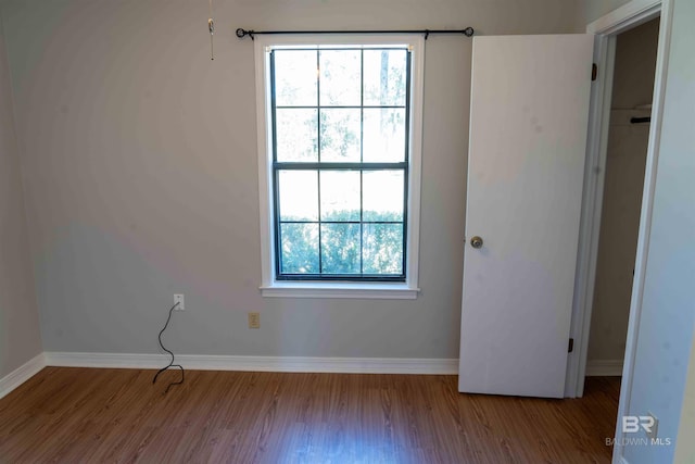 unfurnished room with baseboards, a wealth of natural light, and wood finished floors