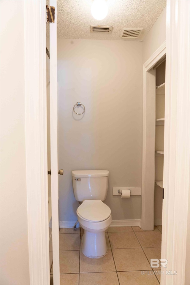 bathroom featuring visible vents, a textured ceiling, toilet, and tile patterned floors