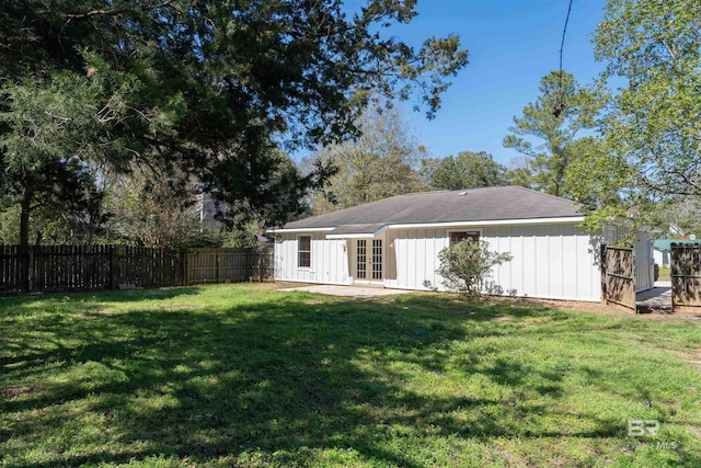 back of house featuring board and batten siding, french doors, a yard, and fence