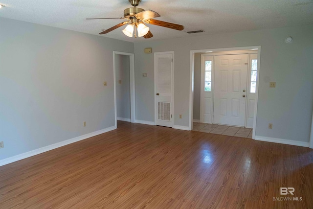 entrance foyer with baseboards, visible vents, ceiling fan, and wood finished floors