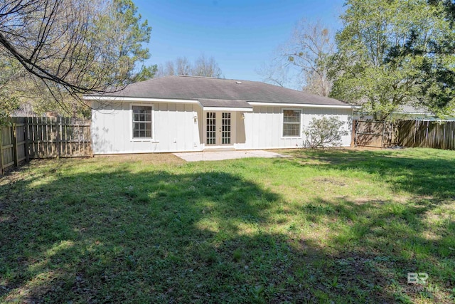 rear view of property with a yard, a fenced backyard, board and batten siding, and french doors