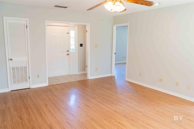 unfurnished room with light wood finished floors, ceiling fan, visible vents, and baseboards