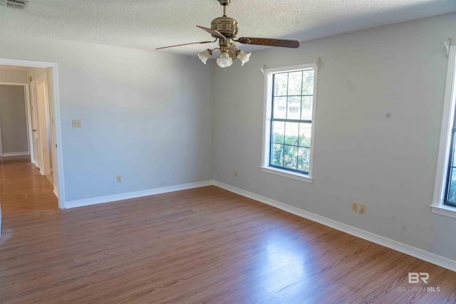 empty room featuring a textured ceiling, baseboards, and wood finished floors