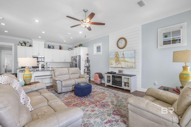 living room featuring hardwood / wood-style floors, ceiling fan, and ornamental molding