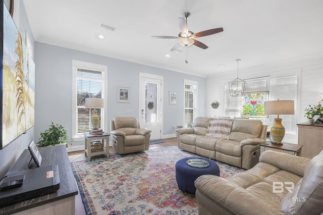 living room with hardwood / wood-style floors, ceiling fan with notable chandelier, and crown molding