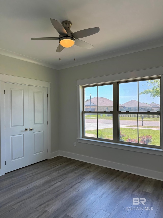 empty room featuring ceiling fan, ornamental molding, and dark wood-type flooring