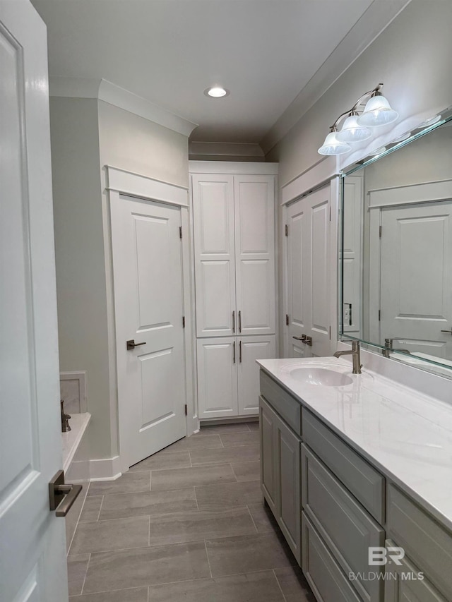 bathroom with crown molding, oversized vanity, and a bathing tub