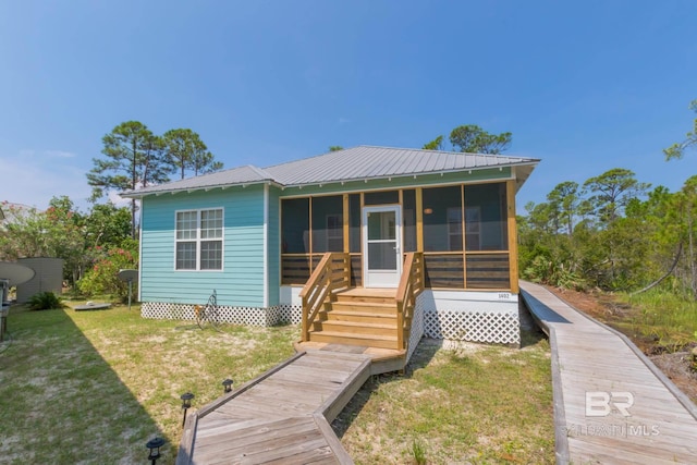 view of front of house with a sunroom, metal roof, and a front yard