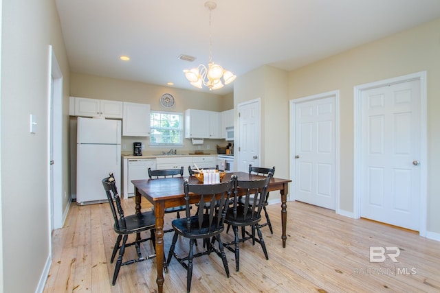 dining area featuring visible vents, a notable chandelier, light wood-style flooring, and baseboards