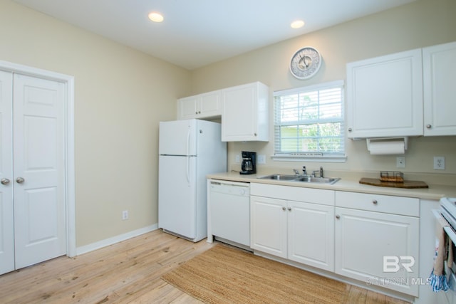 kitchen with light wood finished floors, white appliances, a sink, and white cabinets