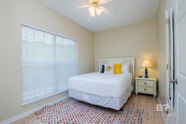 bedroom with light wood-style floors, multiple windows, and baseboards