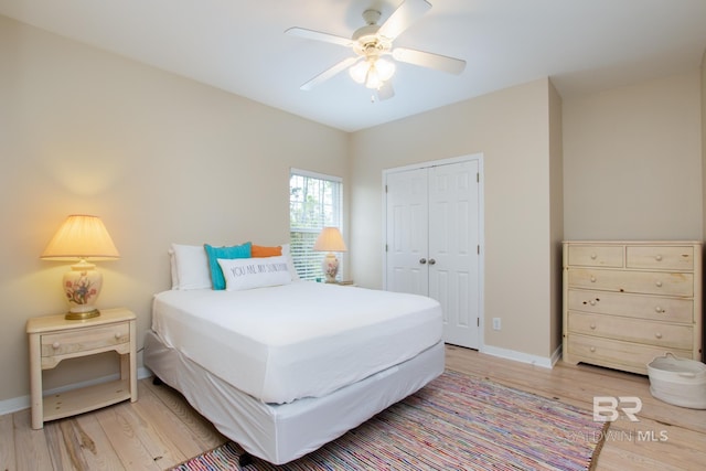 bedroom with light wood-type flooring, ceiling fan, baseboards, and a closet