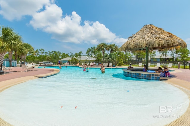 community pool with a jacuzzi, fence, and a patio