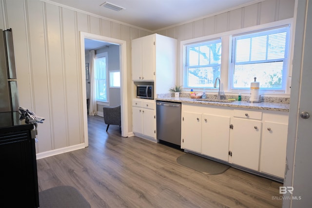 kitchen featuring sink, ornamental molding, appliances with stainless steel finishes, white cabinetry, and wood-type flooring