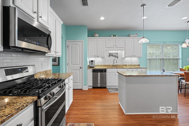 2554 Masters Ct, Mobile, AL 36618 - kitchen with stainless steel appliances, a textured ceiling, decorative backsplash, white cabinetry, and light wood-style flooring