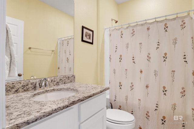 bathroom with walk in shower, vanity, and toilet