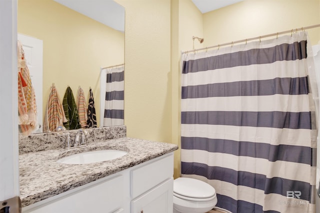 bathroom featuring vanity, walk in shower, and toilet