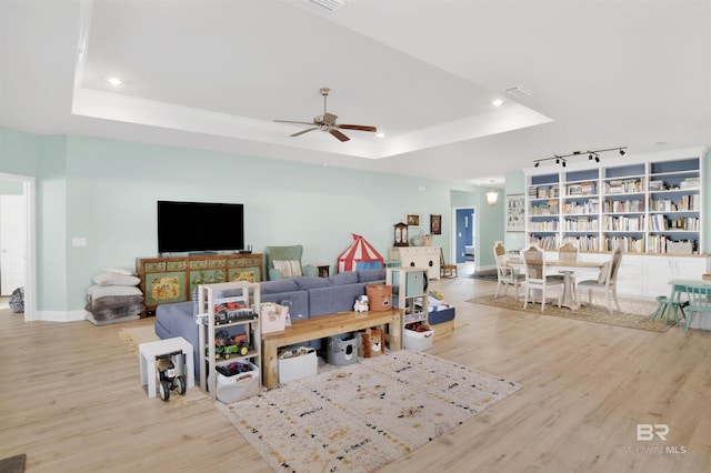 living room with ceiling fan, a raised ceiling, and light hardwood / wood-style floors