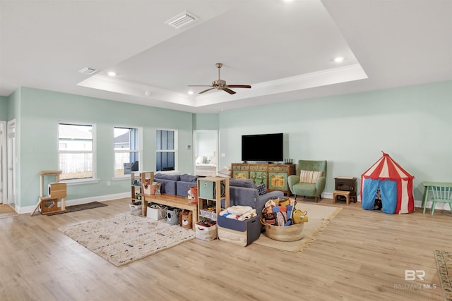 living room with ceiling fan, light hardwood / wood-style floors, and a tray ceiling