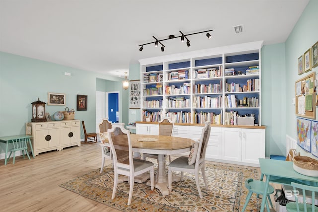 dining space featuring rail lighting and light hardwood / wood-style flooring