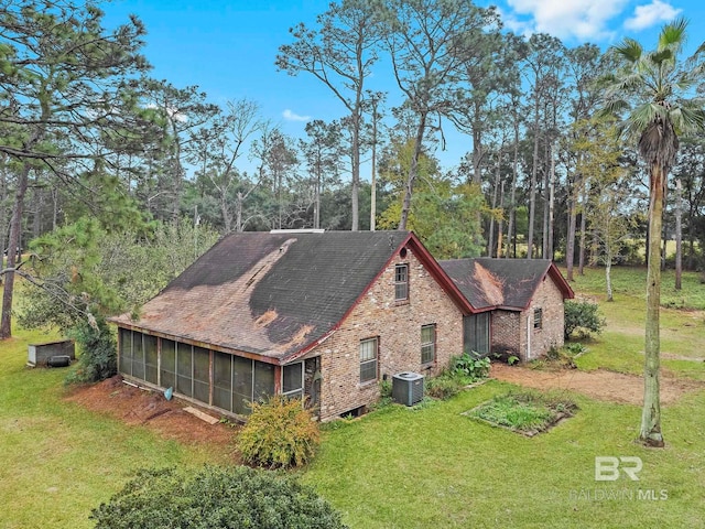 view of side of property with a yard, central air condition unit, and a sunroom