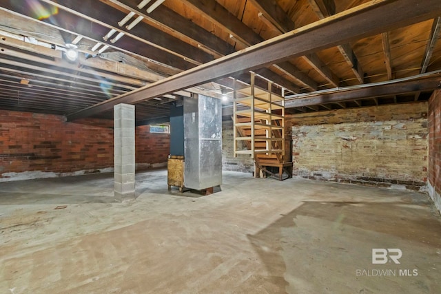 basement featuring heating unit and brick wall