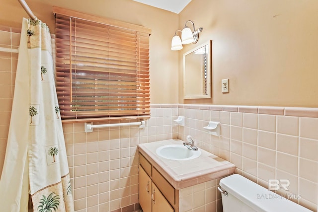 bathroom with a shower with shower curtain, vanity, toilet, and tile walls