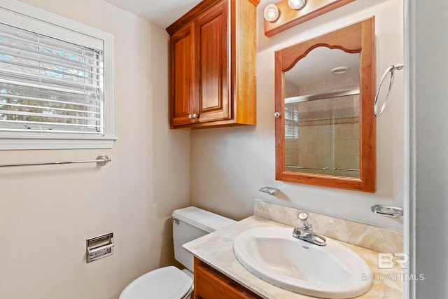 bathroom featuring a shower with door, vanity, and toilet