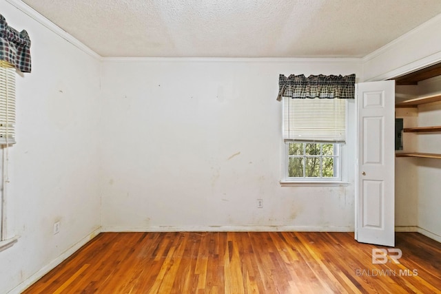 spare room with crown molding, wood-type flooring, and a textured ceiling