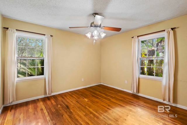 empty room with hardwood / wood-style floors, a healthy amount of sunlight, and a textured ceiling