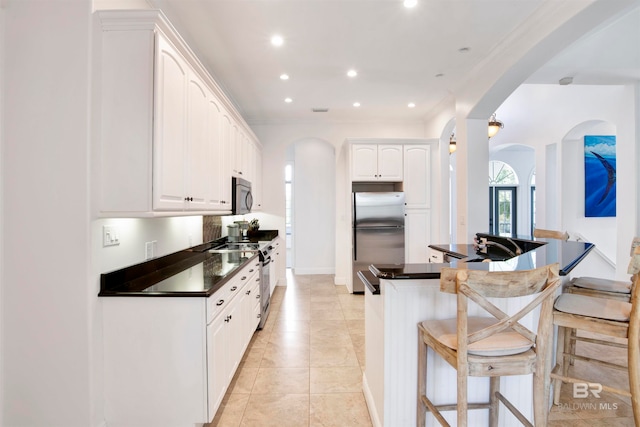 kitchen with crown molding, white cabinets, stainless steel appliances, and a breakfast bar area